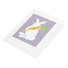 White Easter Bunny on lilac background holding an orange carrot. Card blank inside.