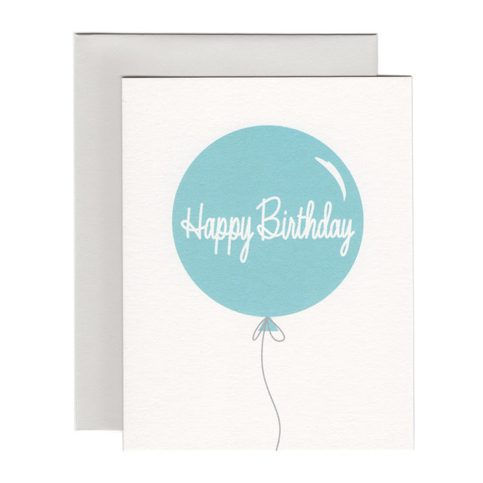 Single elegant large pale blue balloon says Happy Birthday on white background paired with soft gray envelope.
